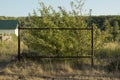 An old rusty metal frame structure in the middle of green bushes and sun-scorched yellow grass and anthills on a sunny summer day Royalty Free Stock Photo