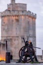 old rusty metal gear wheel in the port of la rochelle. it stands in front of the medieval city\'s famous towers Royalty Free Stock Photo