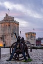 old rusty metal gear wheel in the port of la rochelle. it stands in front of the medieval city's famous towers Royalty Free Stock Photo