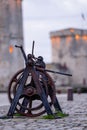 old rusty metal gear wheel in the port of la rochelle. it stands in front of the medieval city\'s famous towers Royalty Free Stock Photo