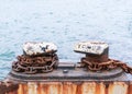 Old, rusty metal mooring mount and large chain on a sea pier close-up on a background of the sea. Royalty Free Stock Photo