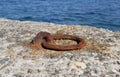 An old rusty metal mooring ring on the mooring wall on a sunny summer day. A device for holding sea vessels in port. Royalty Free Stock Photo