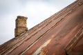 Old rusty metal roof with patches. Repair and renovation. Brick chimney Royalty Free Stock Photo