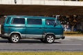 An old, rusty minibus drives down the street. Side view of the van