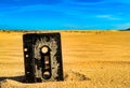 Old rusty music tape cassette in the sand in a desert