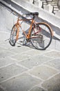 Old rusty orange bicycle against a marble wall Royalty Free Stock Photo