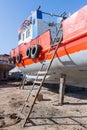 Old rusty orange ship under repairing on grungy dry dock in shipyard in old shipbuilding plant Royalty Free Stock Photo