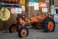 Old rusty orange tractor abandoned behind a garage in a Wild West town