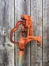 Old, rusty orange Woodford Iowa water hydrant pump against a weathered wooden barn wall Royalty Free Stock Photo