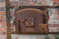 old rusty oven door surrounded by bricks