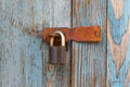 An old rusty padlock on an old cracked wooden door covered with old peeled blue paint Royalty Free Stock Photo