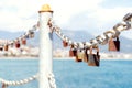 Old rusty padlocks on chain on metal railing against the city and blue sea on sunny day. Close-up. Selective focus. Blurred Royalty Free Stock Photo