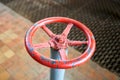 Old rusty painted red valve wheel with swellings and peeling selective focus with extension device over out of focus Royalty Free Stock Photo