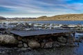 Old rusty pier made of wooden planks on top of rocky boulders at shores of Hafrsfjord fjord in Tananger Royalty Free Stock Photo