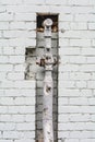 Old rusty pipe with valves on painted white classic brick wall Royalty Free Stock Photo