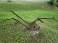 An old rusty plow on a tree stump in the middle of a green lawn on the outskirts of the village Royalty Free Stock Photo