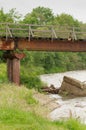 An old, rusty railway bridge over the river with old wooden beams. Royalty Free Stock Photo