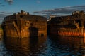 Old rusty red brown barges at sea, reflected in blue water in sunset light. Lake Baikal. Beautiful seascape with abandoned boats Royalty Free Stock Photo