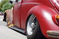 Old rusty red VW Volkswagen car rear fender viewed for restoration in public parking lot