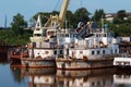 Old rusty river ships in the backwater in summer. Corrosion of metal. Reflection in water. The concept of recycling