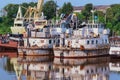 Old rusty river ships in the backwater in summer. Corrosion of metal. Reflection in water. The concept of recycling