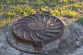 Old rusty round sewage hatchway on the lawn