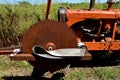 Old rusty saw blade mounted on an orange tractor front