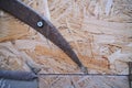 Old rusty scythe on plywood background, closeup of photo.