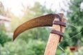 Old rusty scythe on wooden handle in yard of country house