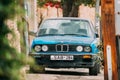 Old rusty sedan car BMW 3 Series E30 parking on street. The BM Royalty Free Stock Photo
