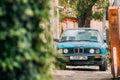 Old rusty sedan car BMW 3 Series, E30, parking on street. The BMW Royalty Free Stock Photo