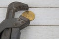 Old rusty silver pipe spanner clamps a golden coin bitcoin