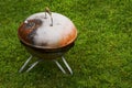 Old rusty small barbeque cooker in a garden. Cheap metal cooking device. Worn out budget way to cook food Royalty Free Stock Photo