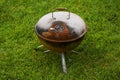 Old rusty small barbeque cooker in a garden. Cheap metal cooking device. Worn out budget way to cook food