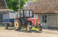 Old rusty small red tractor Ursus C360 with small trailerparked