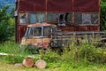 An old rusty stationary car stands by an old rusty tin shed on the edge of the forest Royalty Free Stock Photo