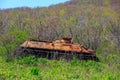 An old rusty tank stands in the middle of thick grass near the seashore. The abandoned battle tank rusted with old age Royalty Free Stock Photo