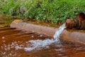 An old rusty tap from which an artificial lake is filled. Rusty sediment at the bottom of the lake Royalty Free Stock Photo