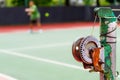 Old and rustic tennis net reel post with blurred person taking tennis lesson on the background Royalty Free Stock Photo