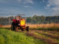 Old rusty tractor with grass cutting machine in a agriculture field with tall grass at stunning sunrise. Farming industry. Royalty Free Stock Photo