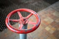 Old rusty valve wheel painted red paint with swellings and peeling selective focus with extension device over out of focus Royalty Free Stock Photo