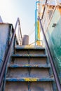 Old rusty vertical staircase with paint peeling off, leading to the upper deck of the wreck of cargo ship Royalty Free Stock Photo