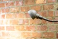 Old and rusty vintage industrial lamp shedding light on a red brick wall Royalty Free Stock Photo