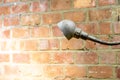 Old and rusty vintage industrial lamp shedding light on a red brick wall