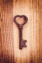 Old rusty vintage key in the shape of a heart, wood background. Love Valentine`s day greeting card Royalty Free Stock Photo