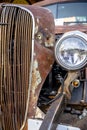 Old rusty vintage retro car with a bent grill and a new headlight of a provincial town standing at an exhibition on the street