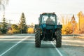 Old rusty vintage tractor of blue color is driving along the road in a village in Russia in summer, rural life in the Saratov Royalty Free Stock Photo