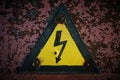 Old, rusty warning about danger and high voltage in form lightning yellow background