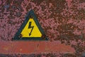 Old, rusty warning about danger and high voltage in form lightning yellow background