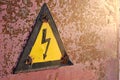 Old, rusty warning about danger and high voltage in form lightning yellow background